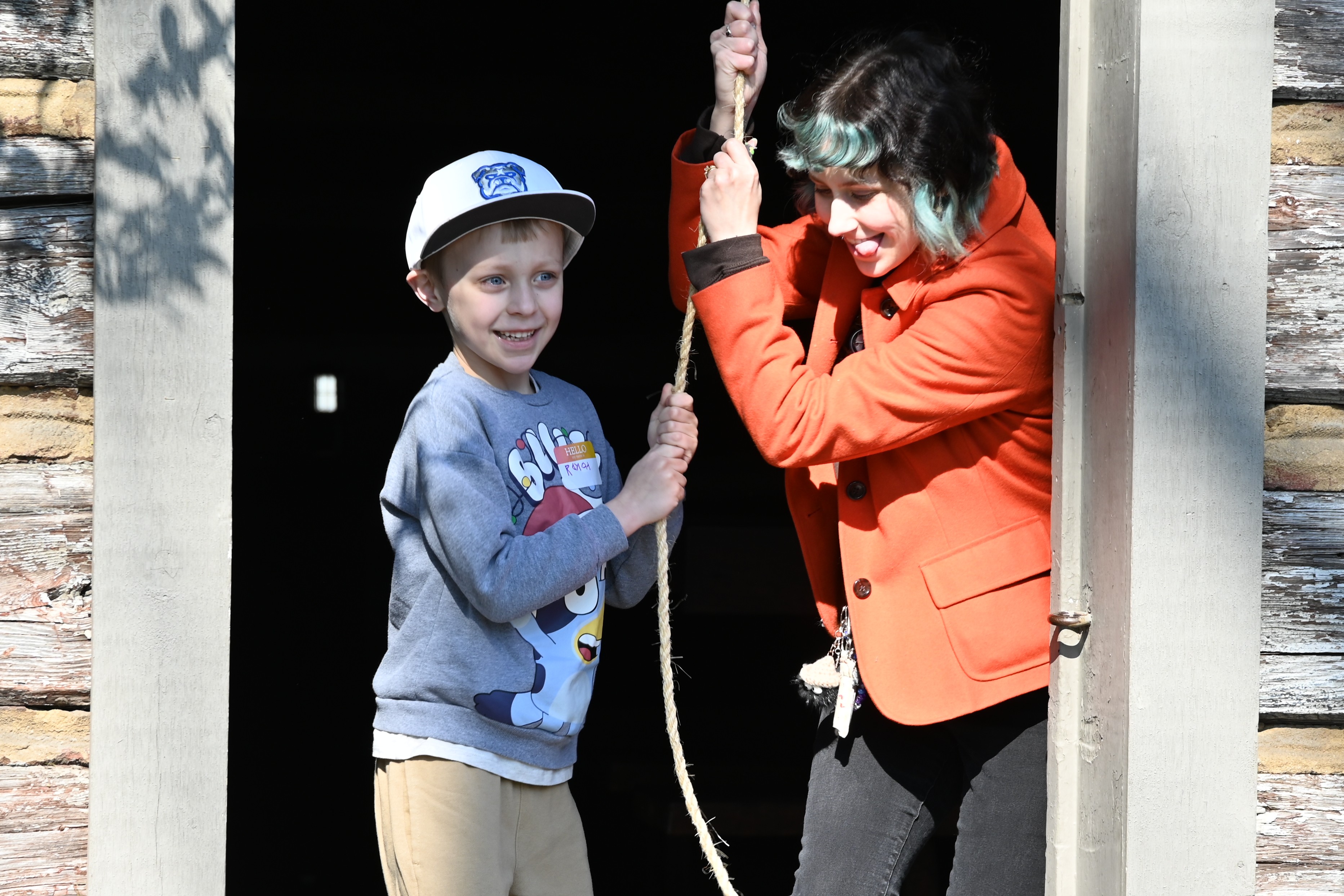 Youth services associate Mara helps a youngster ring the bell at the inaugural Literacy Bell Celebration of Reading.