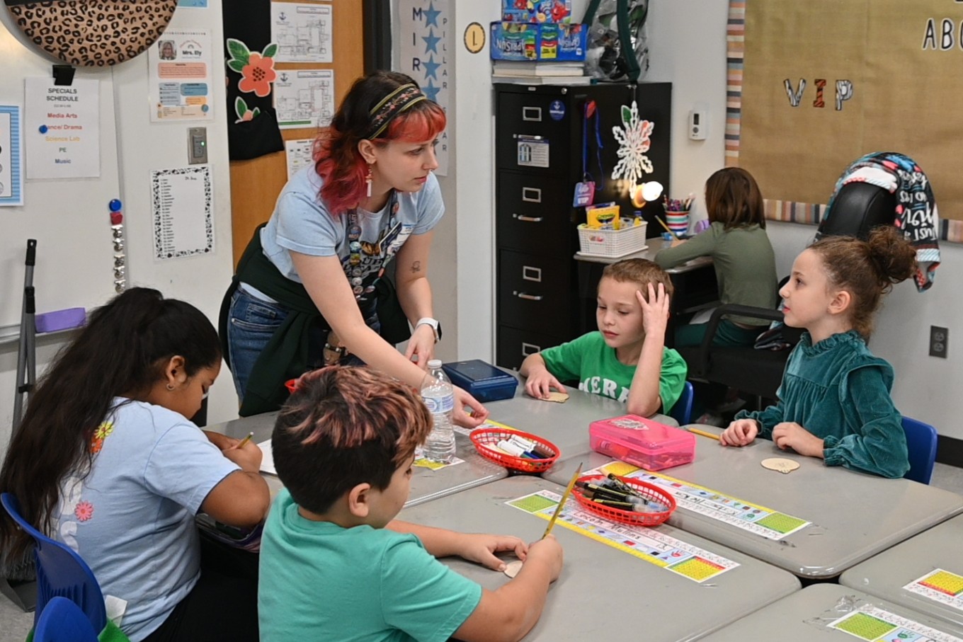 Mara works with a group of students as they paint ornaments at Edna L. Toliver Intermediate School.