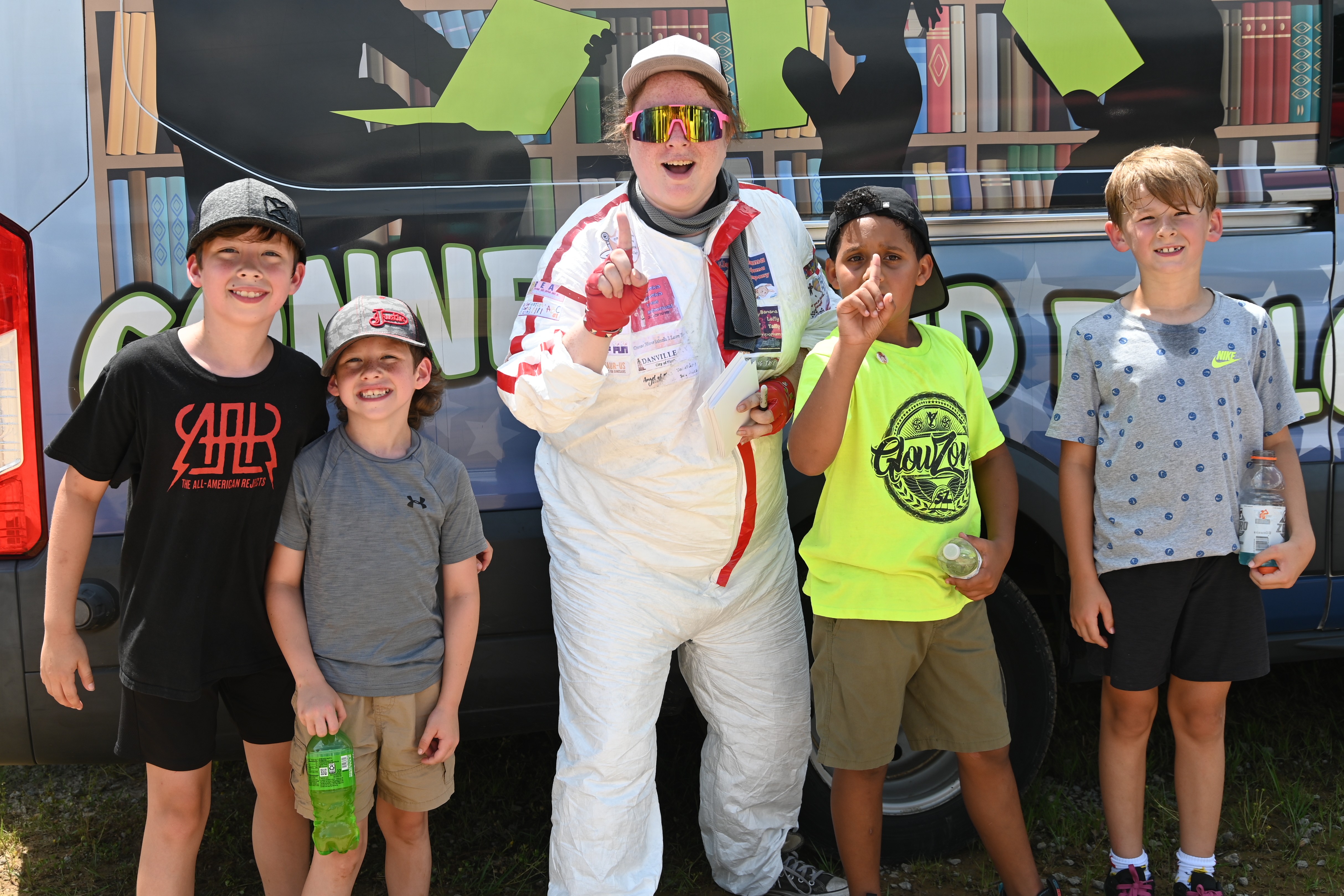 Outreach associate Katie poses with a few of her fans after winning the bookmobile race at the Reading and Racecars event at Ponderosa Speedway.